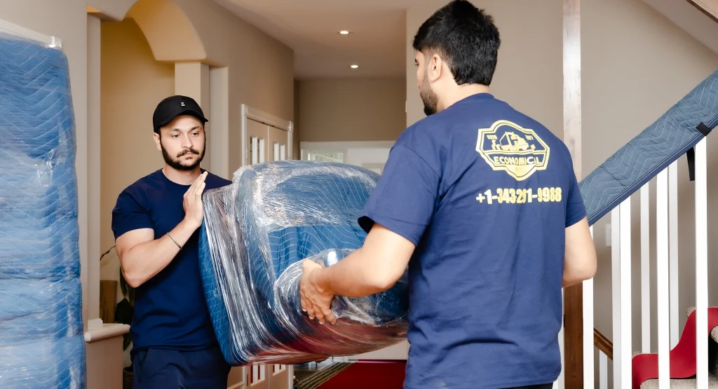 Economical movers carrying wrapped furniture into a suburban home during a residential move in Canada.
